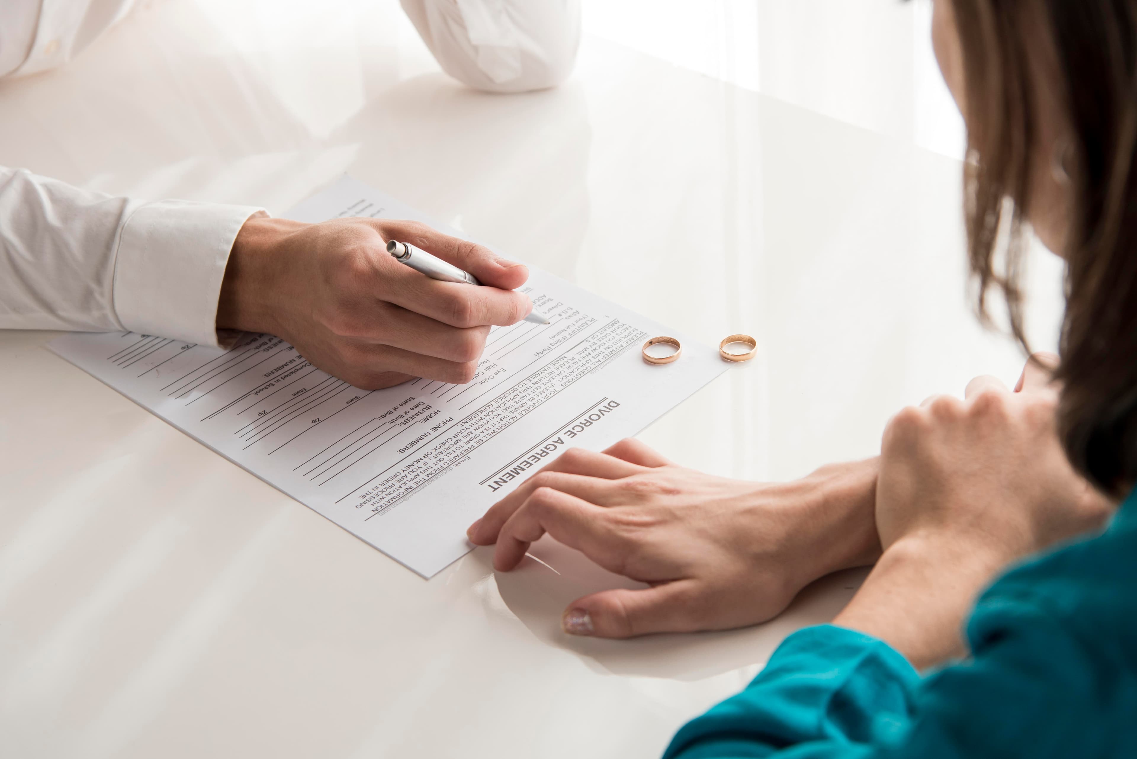 Hands with wedding rings resting on legal documents